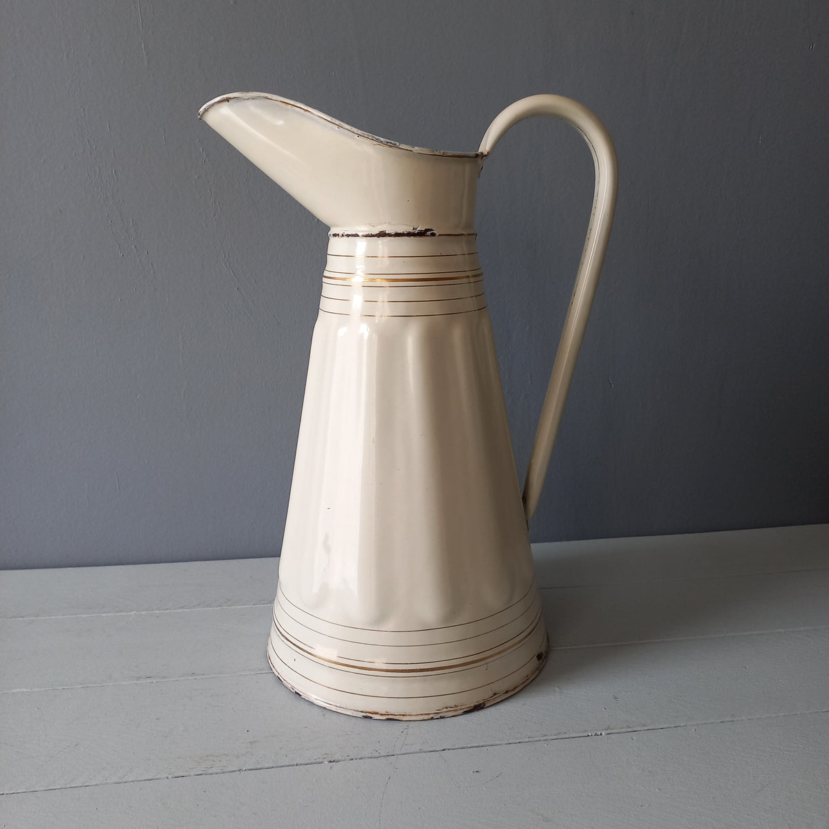 Large antique enamel metal pitcher in cream color with gold trim from France