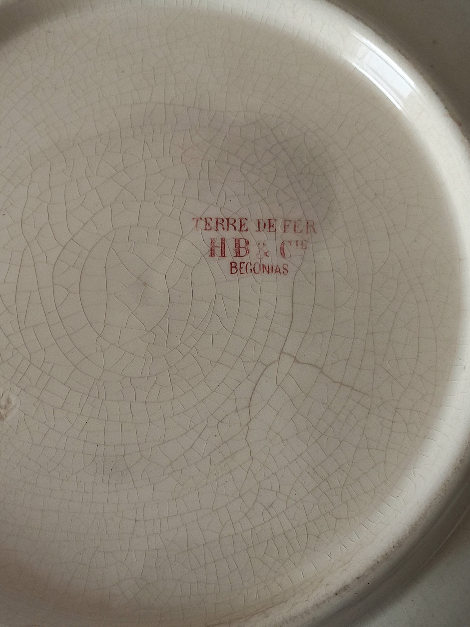 A large French ironstone bowl with deep pink floral pattern on a creamy white base. This antique piece has aged naturally over time, showing fine crazing, tea-staining, and small imperfections that reflect its long history.