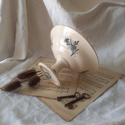 A beautiful antique compote or footed bowl by French manufacturer Longchamp. The main colour is a warm cream/white with blue floral transferware pattern.