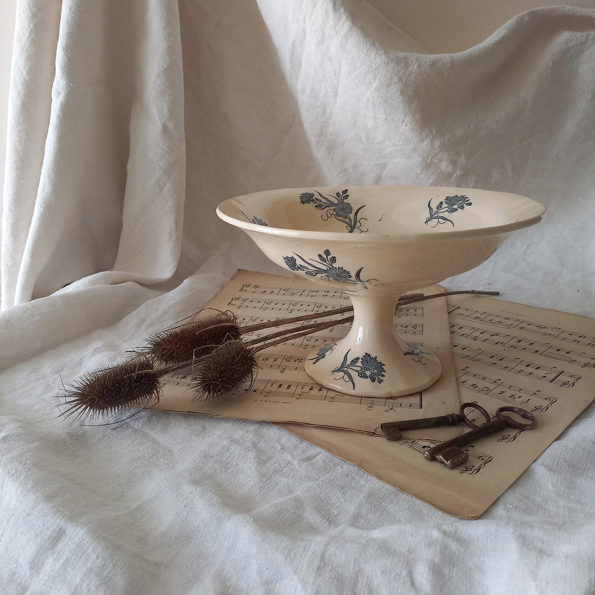 A beautiful antique compote or footed bowl by French manufacturer Longchamp. The main colour is a warm cream/white with blue floral transferware pattern.