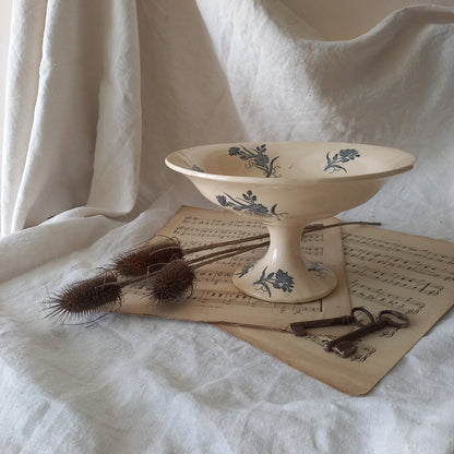 A beautiful antique compote or footed bowl by French manufacturer Longchamp. The main colour is a warm cream/white with blue floral transferware pattern.