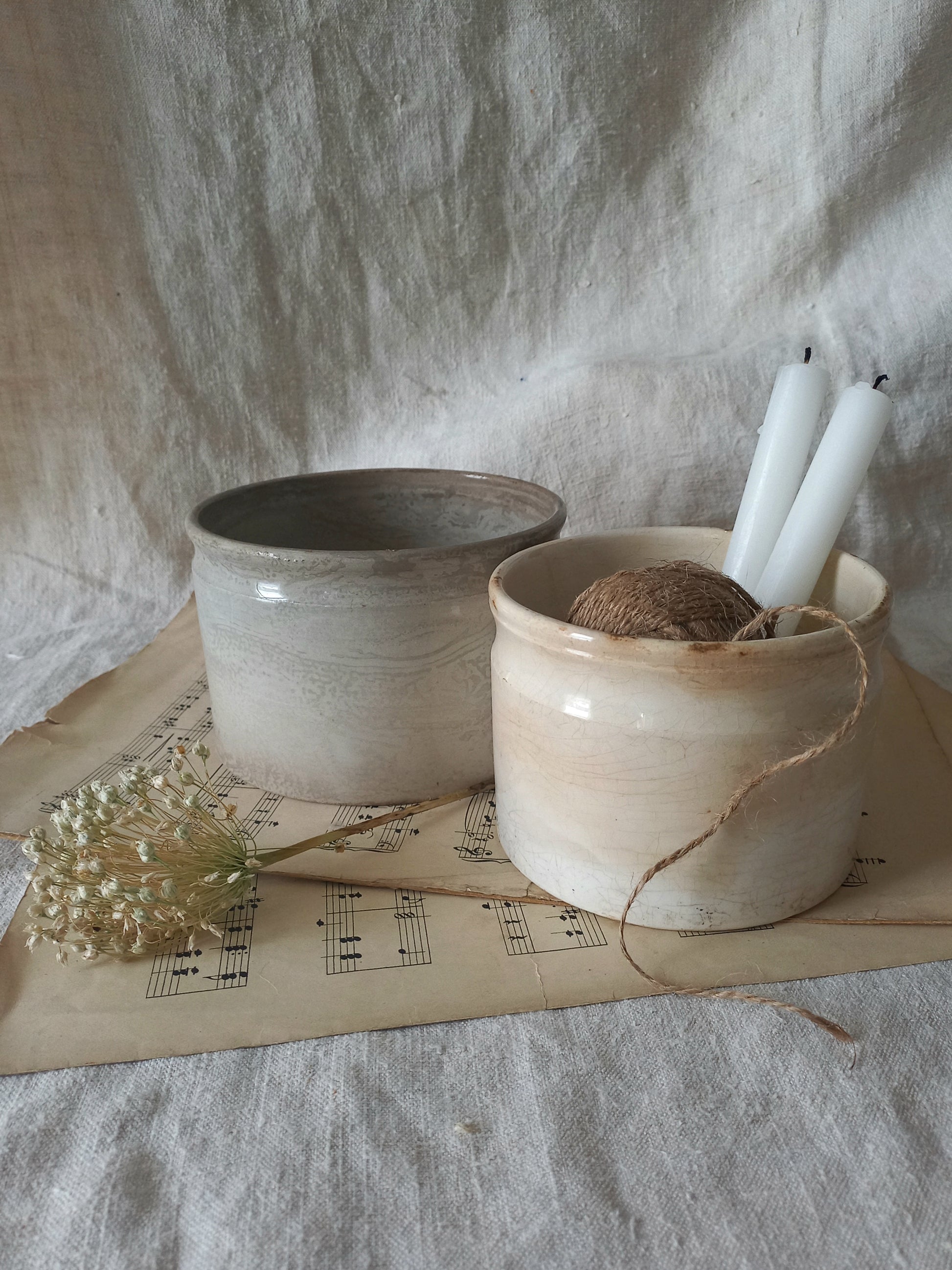 Two ceramic pots on a surface with a piece of music sheet paper underneath.