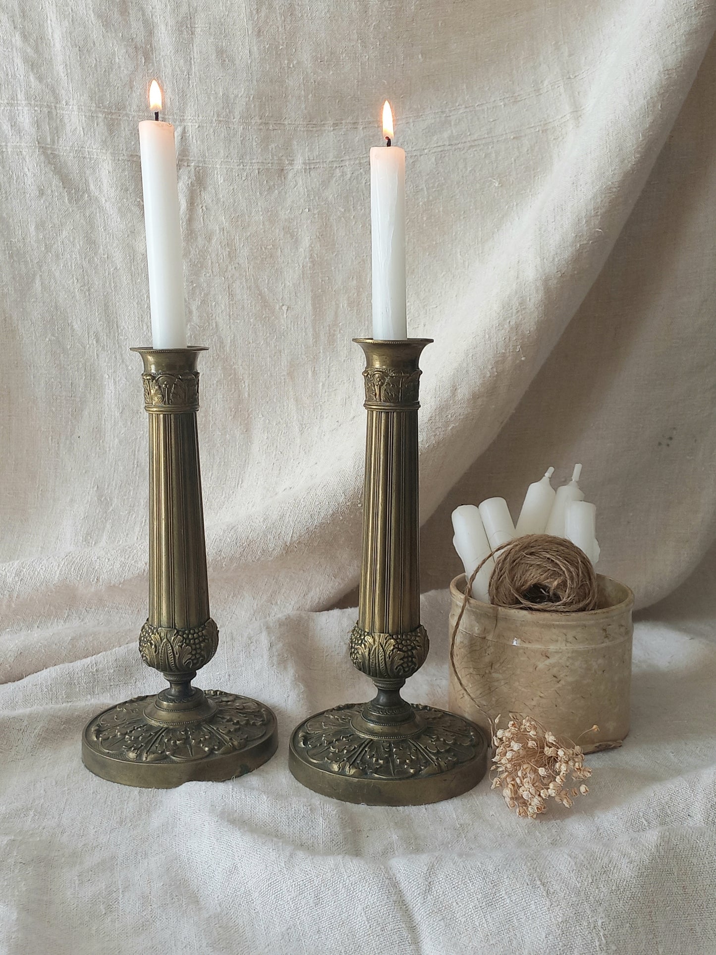Pair of beautiful French antique decorative candle holders with Empire styling on a beige background.