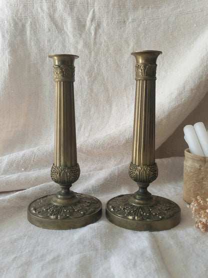 Pair of beautiful French antique decorative candle holders with Empire styling on a beige background.