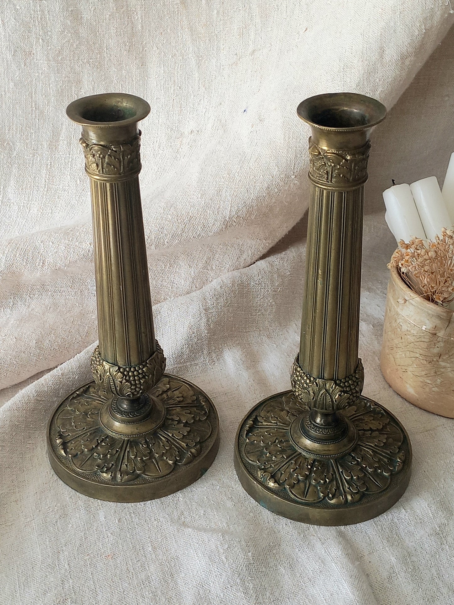 Pair of beautiful French antique decorative candle holders with Empire styling on a beige background.