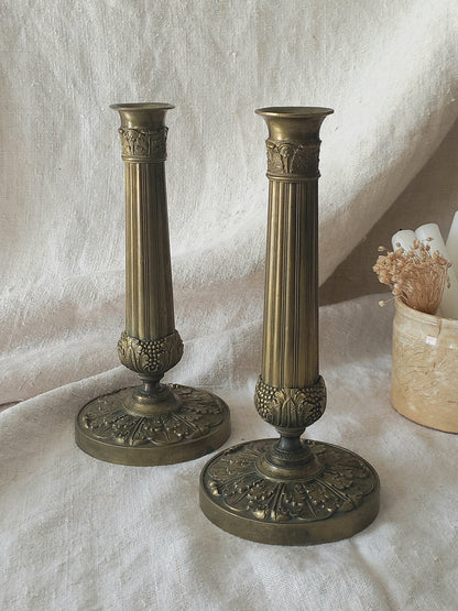 Pair of beautiful French antique decorative candle holders with Empire styling on a beige background.