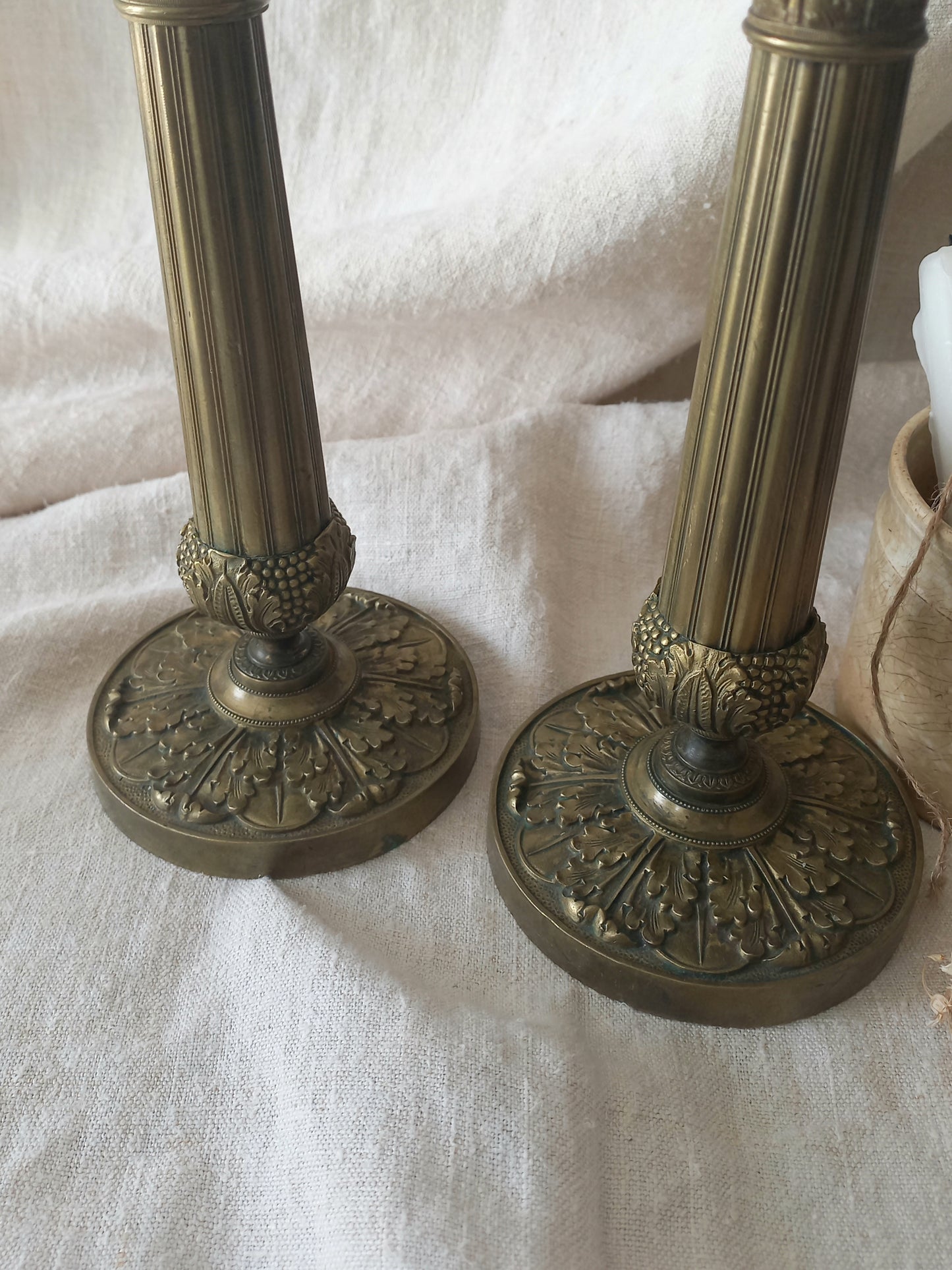 Detail of a pair of beautiful French antique decorative candle holders with Empire styling on a beige background.