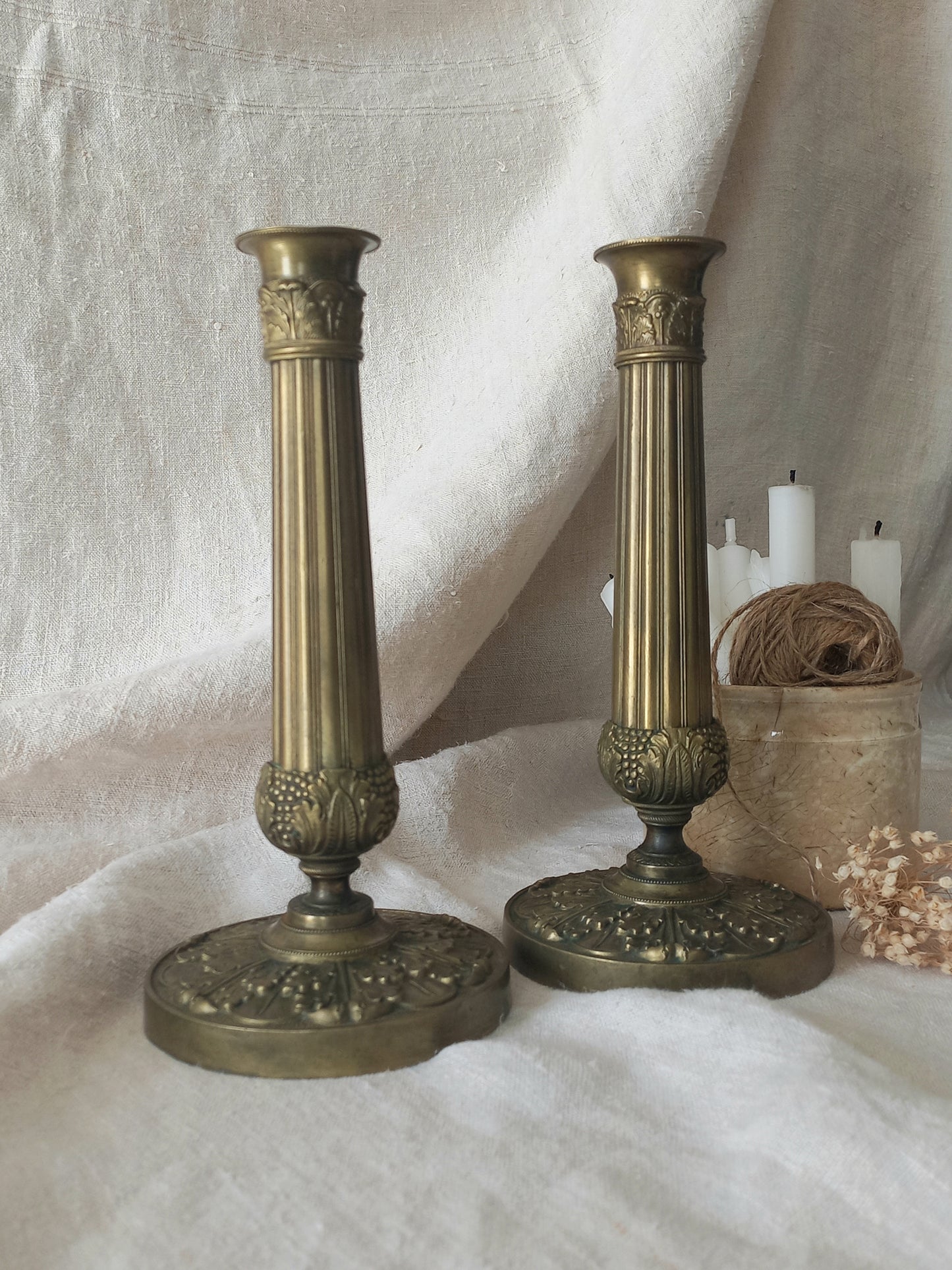 Pair of beautiful French antique decorative candle holders with Empire styling on a beige background.