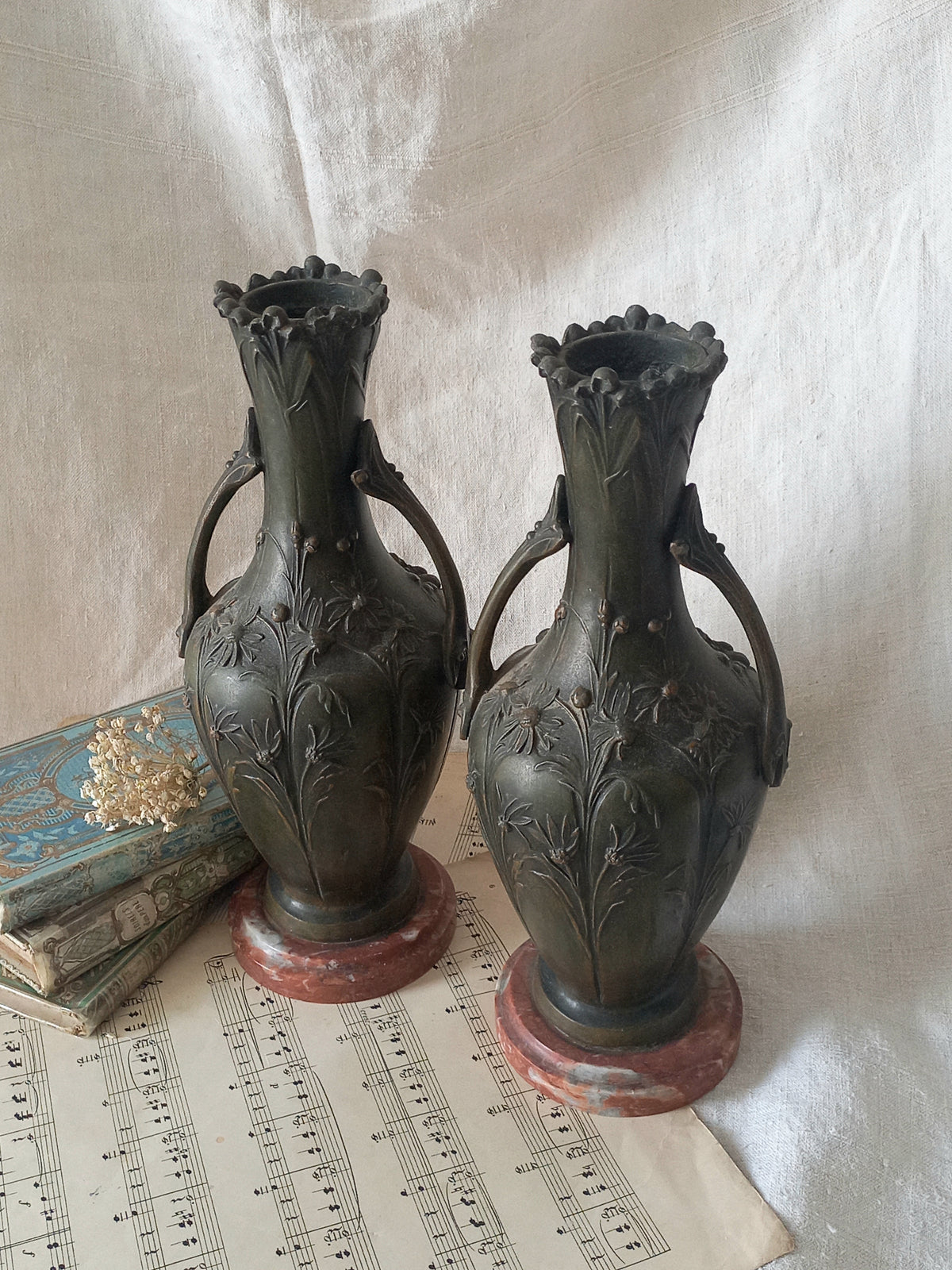 A stunning pair of decorative art nouveau vase/urn ornaments made from metal and finished in a stunning shade of green depicting organic floral decoration in relief.