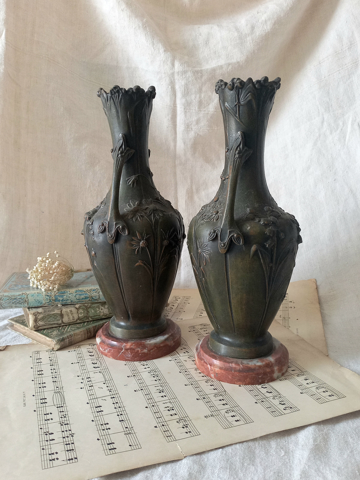 A stunning pair of decorative art nouveau vase/urn ornaments made from metal and finished in a stunning shade of green depicting organic floral decoration in relief.