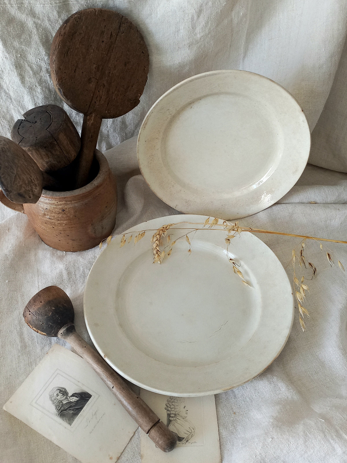 White antique plates with wooden spoons on a textured fabric background