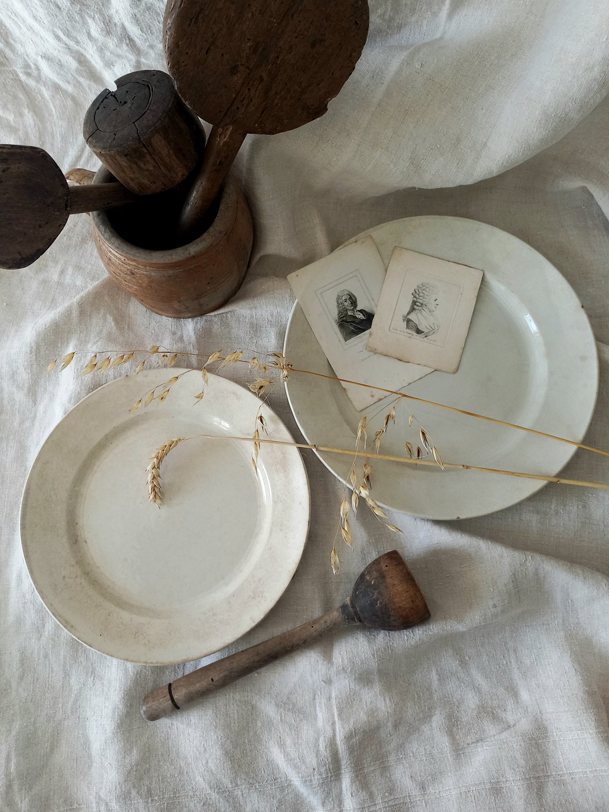 White ceramic plates with wooden utensils on a textured white surface