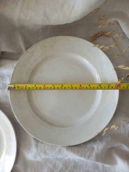 Antique white plate with a measuring tape indicating its diameter on a textured surface.