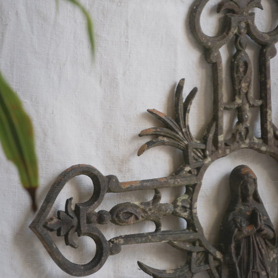 A large French antique crucifix in cast or wrought iron, featuring a figure of the Madonna at its center. Likely once part of a larger architectural structure, this rare piece carries visible signs of age and long exposure to the elements.