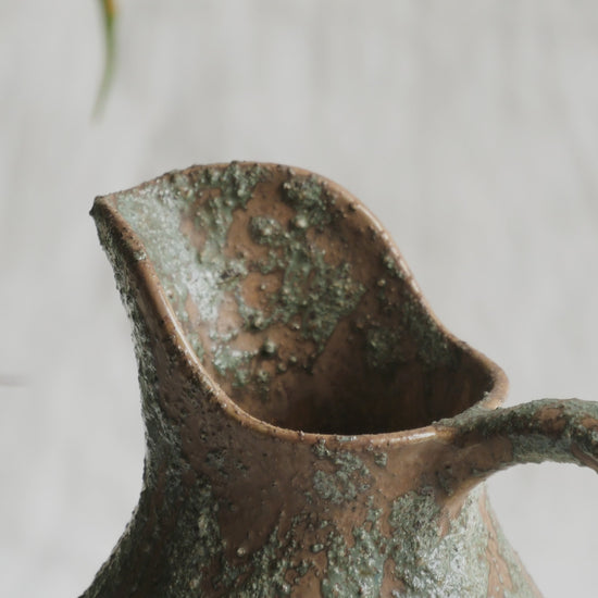 An artisan-made vintage pottery pitcher or jug that purchased in south west France. This piece is wonderful in its earthy tones of brown with a green pattern in relief all over the pitcher and would make a great piece of home decor or addition to a pottery/stoneware collection.