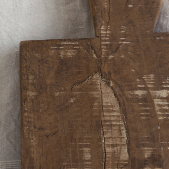 A large vintage wooden chopping board from south west France, shaped by years of use and hand-worn edges. Its rough texture and deep patina tell the story of daily bread, shared meals, and time well lived.