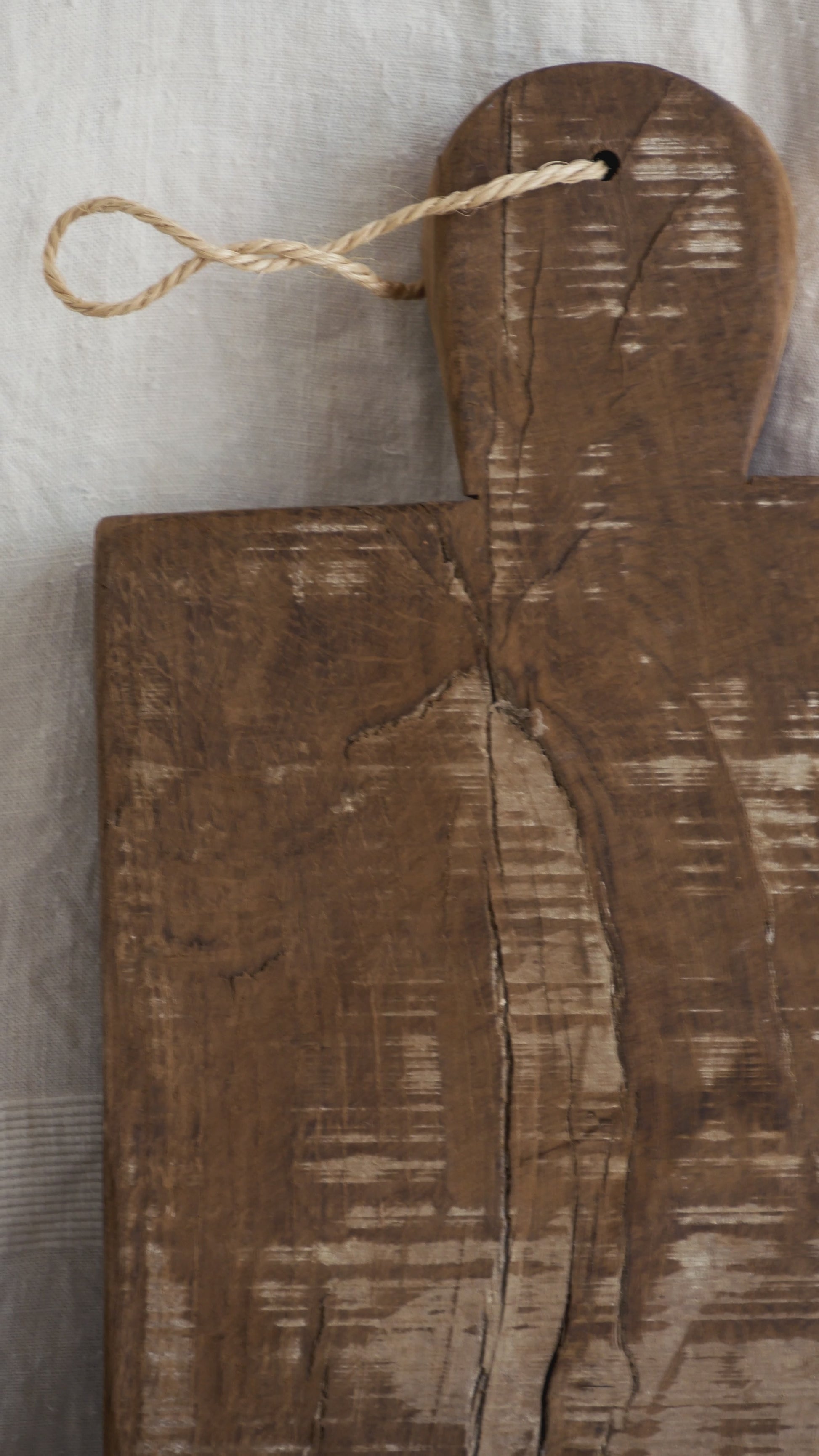 A large vintage wooden chopping board from south west France, shaped by years of use and hand-worn edges. Its rough texture and deep patina tell the story of daily bread, shared meals, and time well lived.