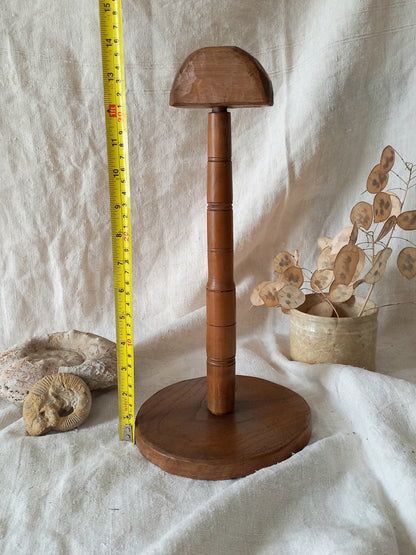 Wooden hat stand with a measuring tape on a textured white background