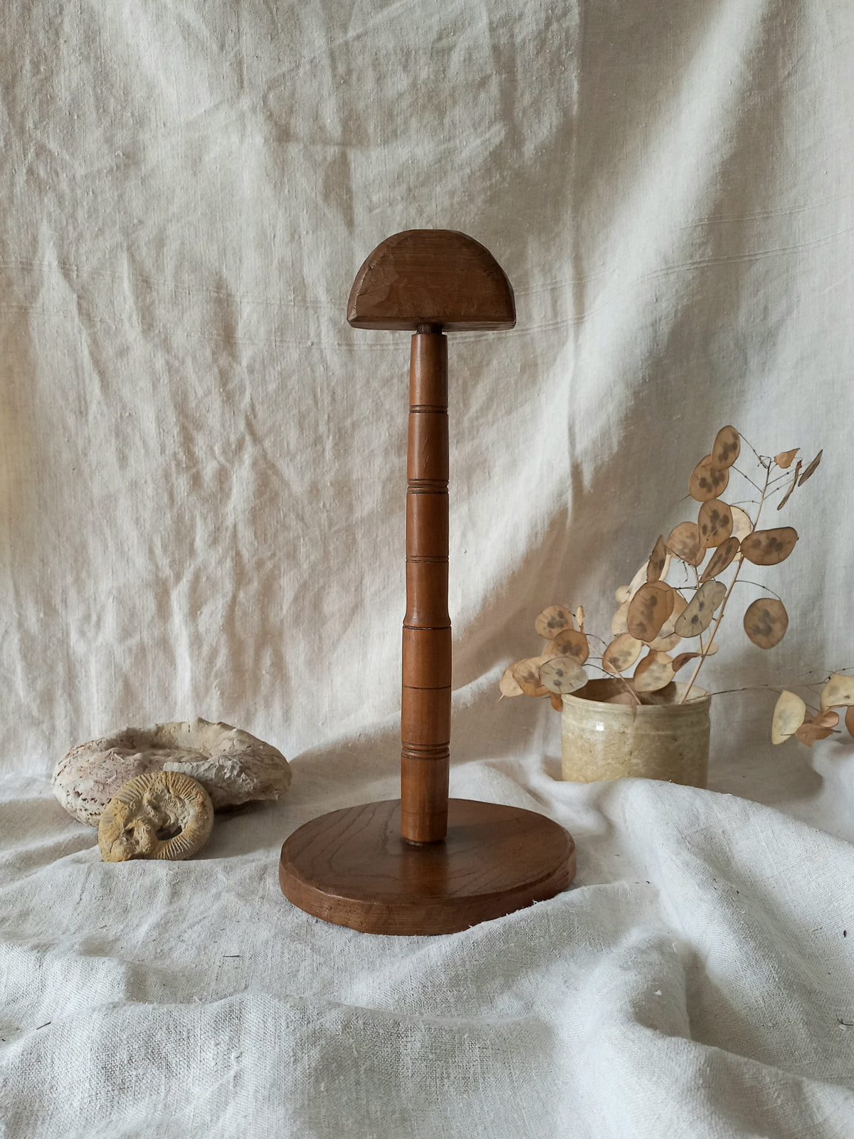 vintage wooden hat stand on a textured white fabric background