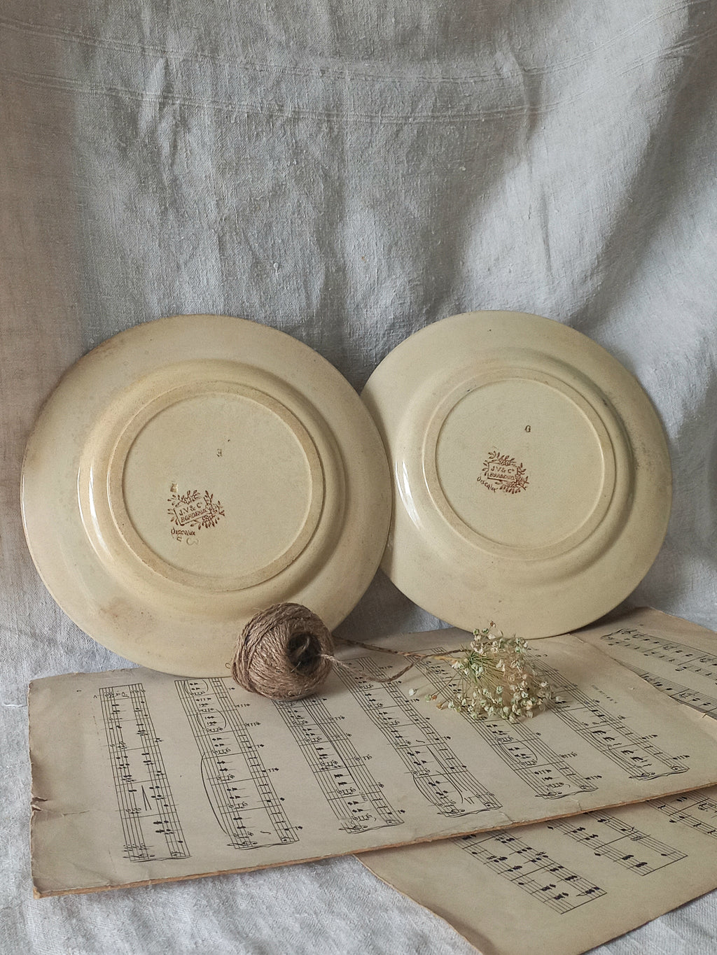 Two ceramic plates with a logo on a surface with an old book and twine.