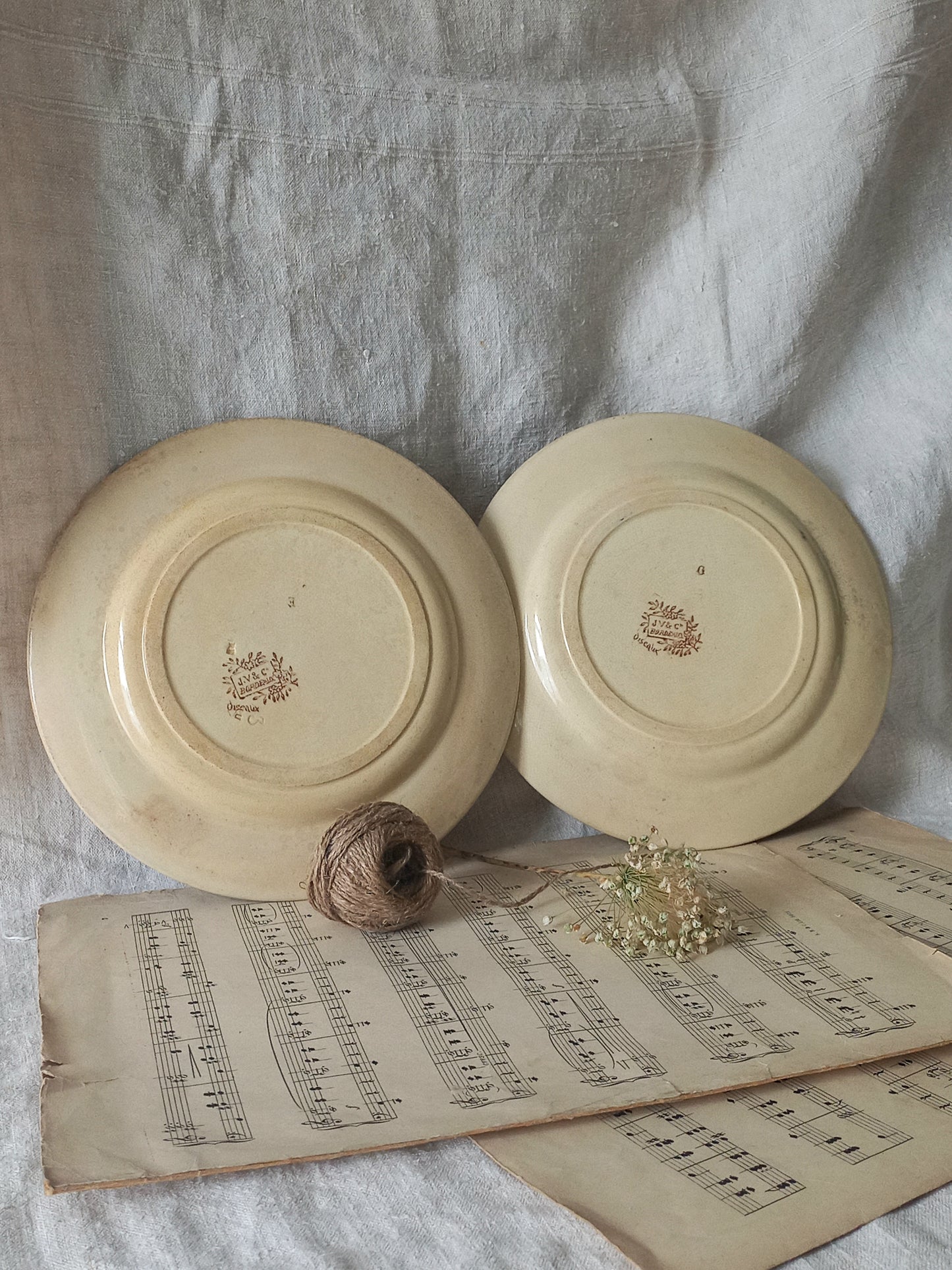 Two ceramic plates with a logo on a surface with an old book and twine.