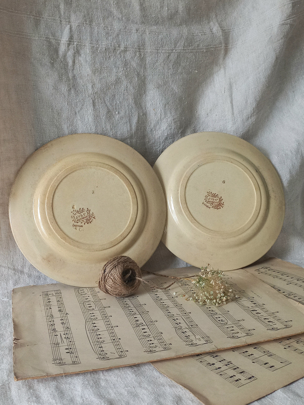Two ceramic plates with a logo on a surface with an old book and twine.