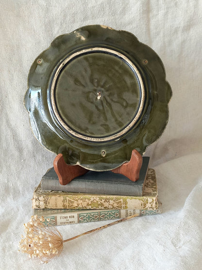 Rear of decorative plate with a scene of Joan of Arc on a horse, surrounded by decorative elements on a white background.
