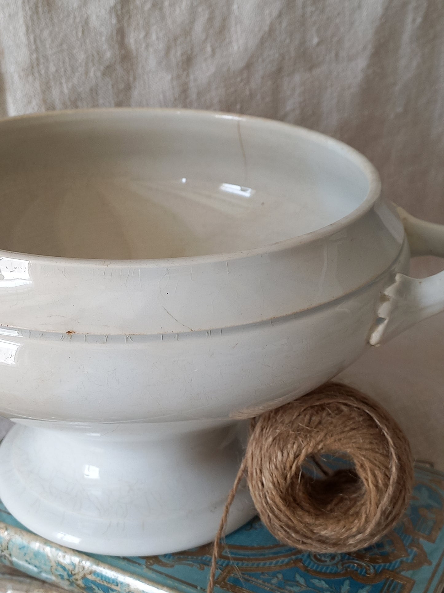 White ceramic bowl with a ball of twine on a textured surface