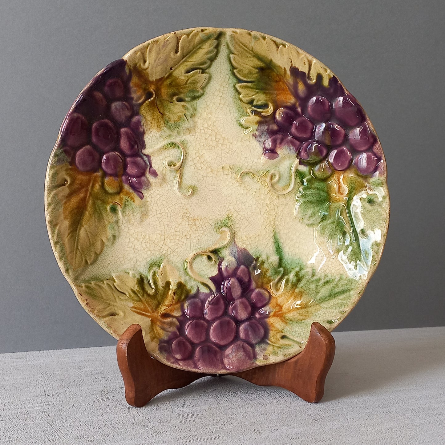 Small and beautiful French antique crazed majolica plate with a wonderful colour scheme depicting dark purple grapes and green foliage; this wonderful old plate will make an excellent addition to a collection or as a stand-alone display piece.