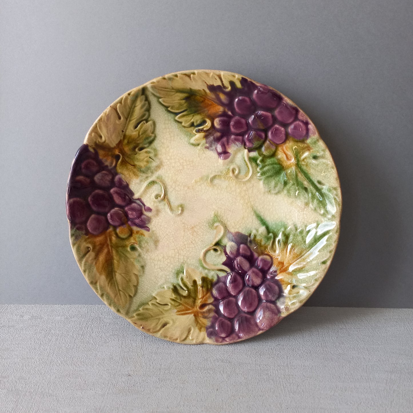 Small and beautiful French antique crazed majolica plate with a wonderful colour scheme depicting dark purple grapes and green foliage; this wonderful old plate will make an excellent addition to a collection or as a stand-alone display piece.