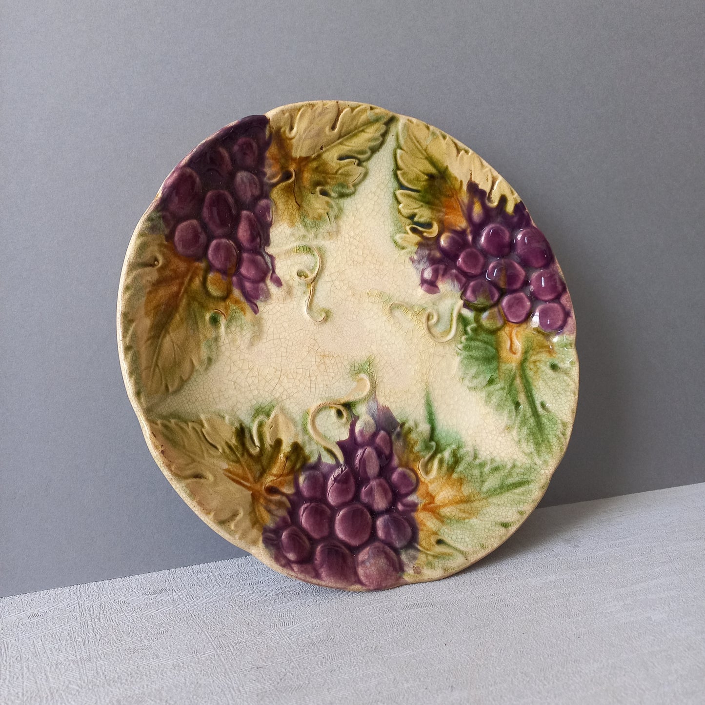 Small and beautiful French antique crazed majolica plate with a wonderful colour scheme depicting dark purple grapes and green foliage; this wonderful old plate will make an excellent addition to a collection or as a stand-alone display piece.