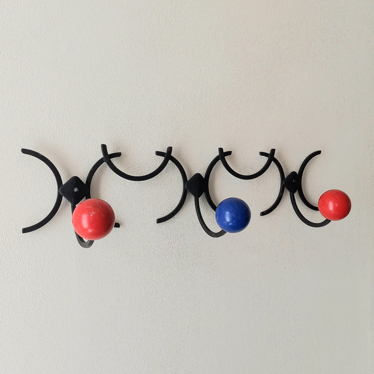 An original French vintage mid-century 'atomic' coat rack, a rare find these days and a wonderful piece of practical home decor. The black frame-work that holds the coloured pegs/balls is made from strong cast iron and there are two screw holes so that you can immediately fix the coat rack to your wall.