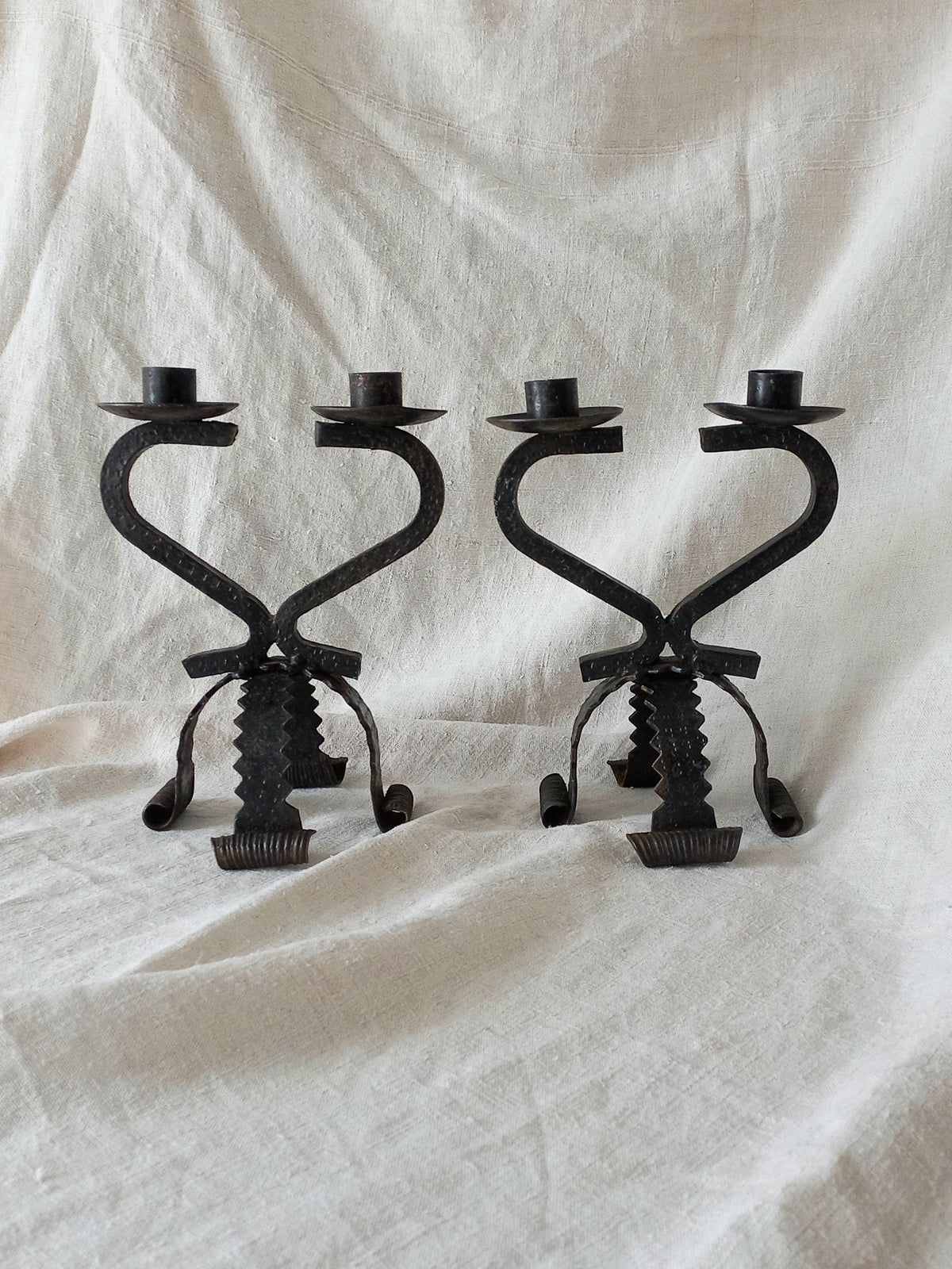 Two black metal candle holders on a white fabric background