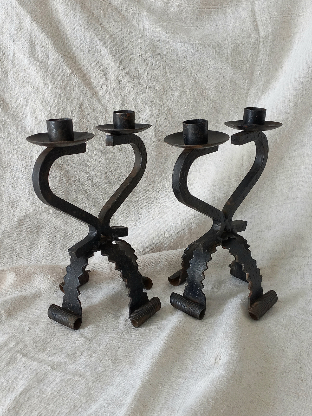 Two black metal candle holders on a white fabric background
