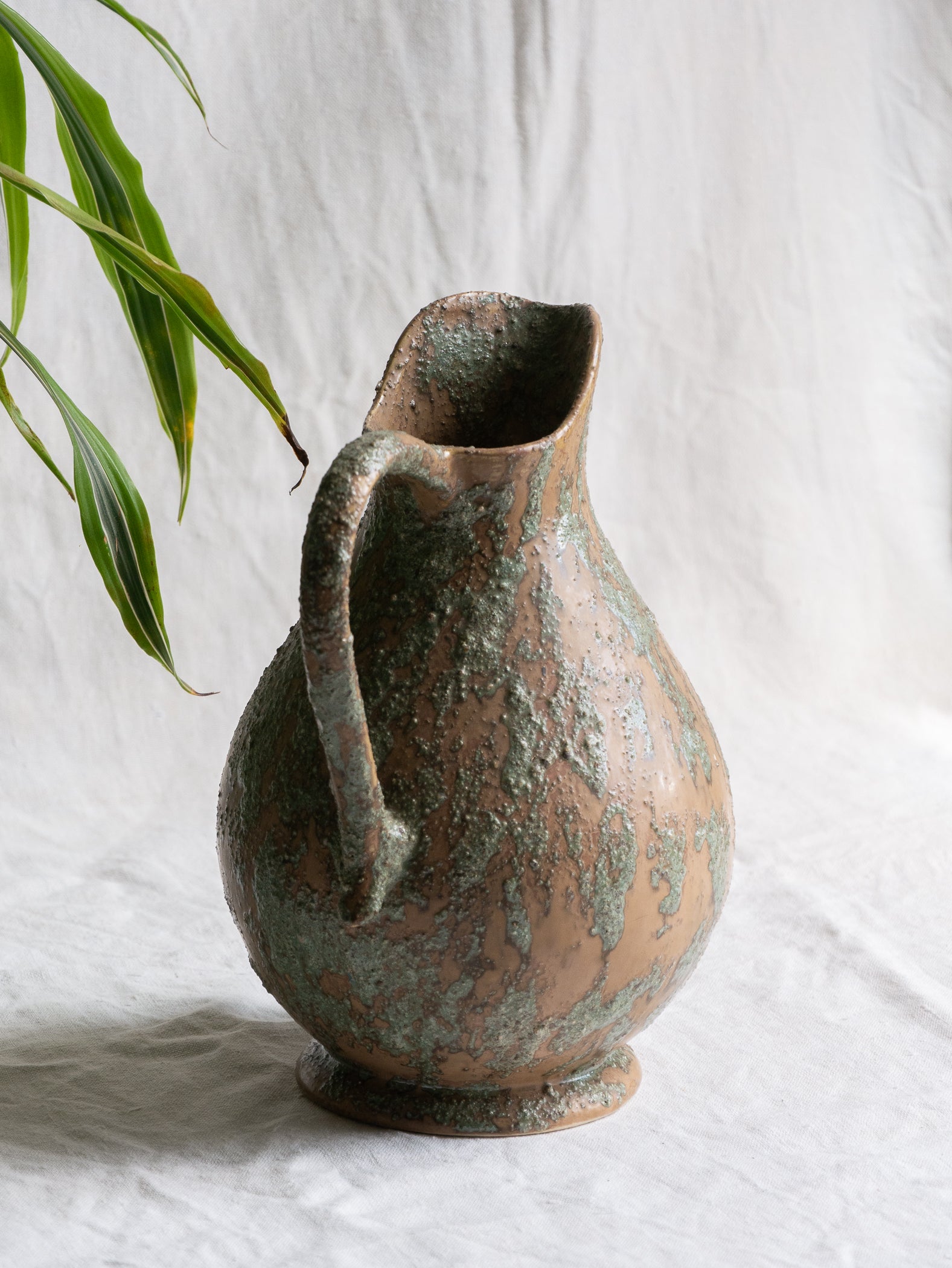 An artisan-made vintage pottery pitcher or jug that purchased in south west France. This piece is wonderful in its earthy tones of brown with a green pattern in relief all over the pitcher and would make a great piece of home decor or addition to a pottery/stoneware collection.