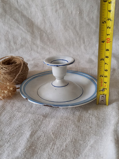 White enamel candle holder with blue rim and measuring tape on a textured surface