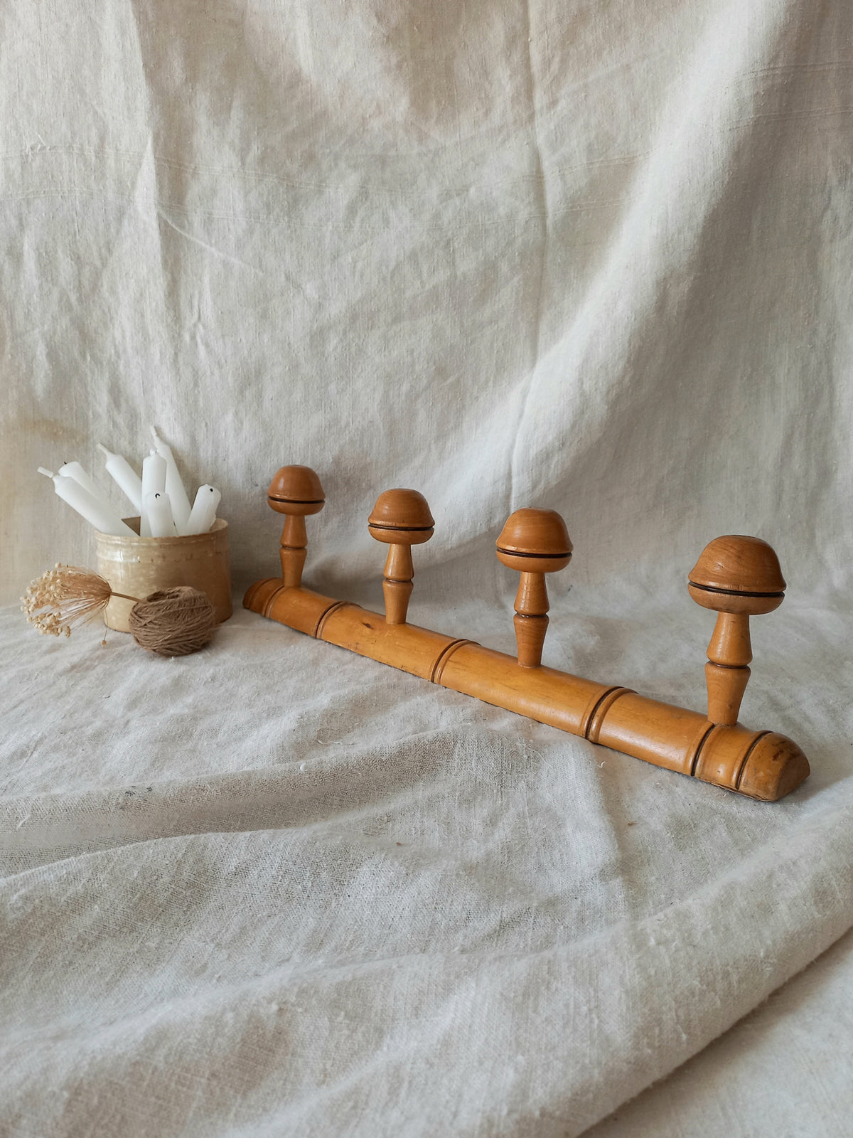 4 peg faux bamboo wooden coat rack on a textured white fabric background