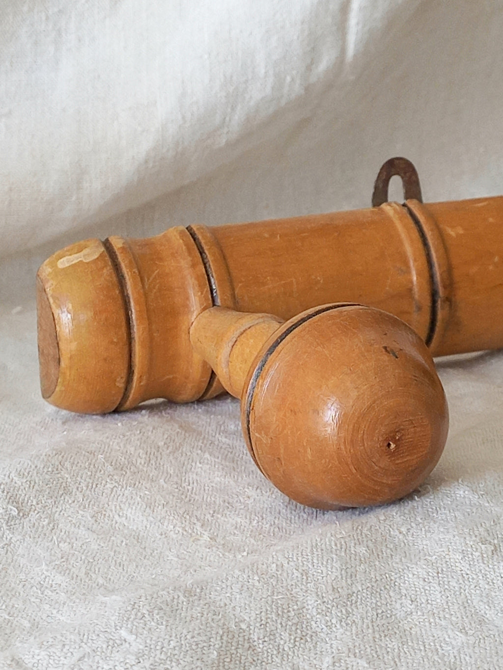 Close-up of a 4 peg faux bamboo wooden coat rack on a textured white fabric background