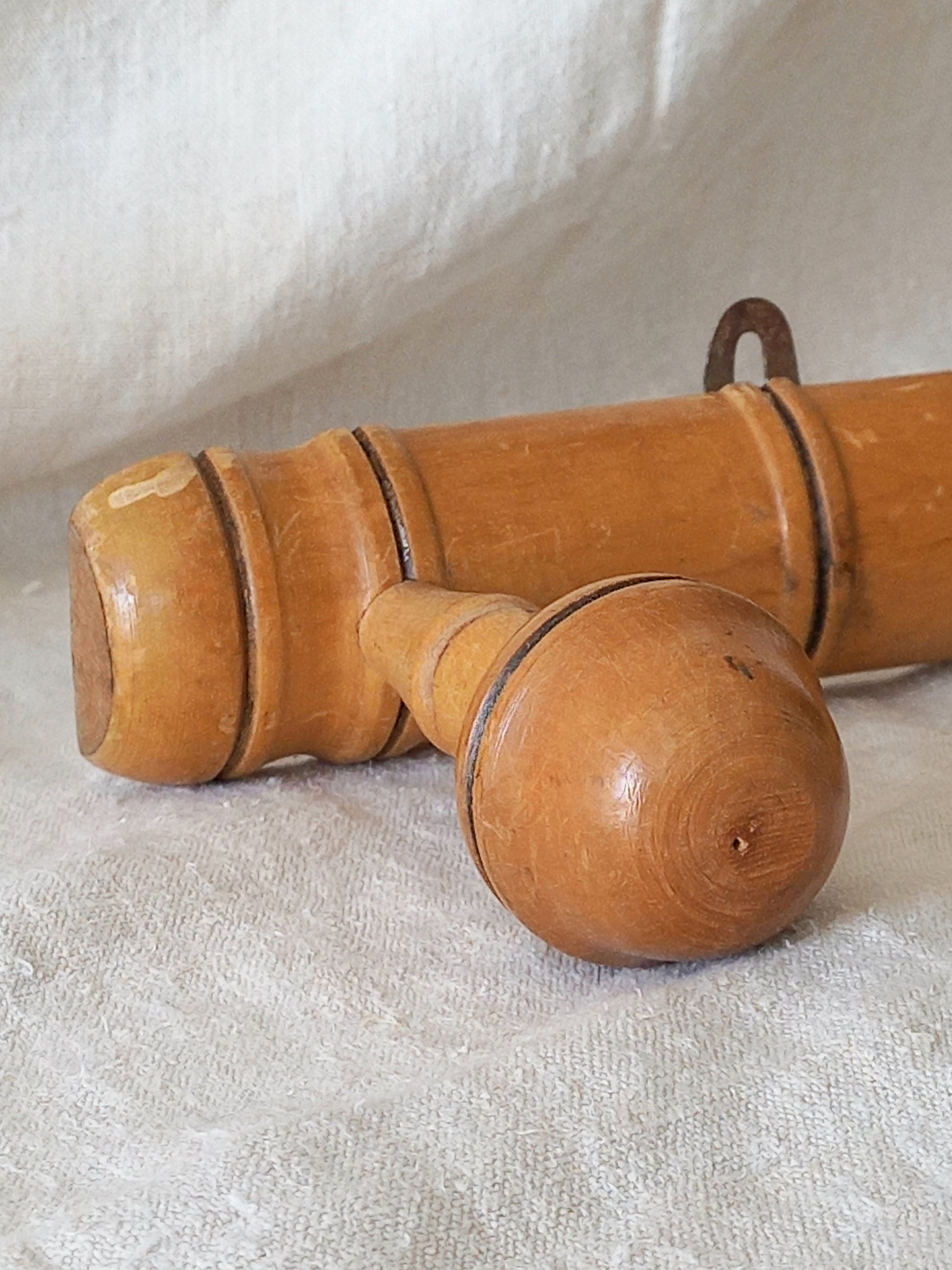 Close-up of a 4 peg faux bamboo wooden coat rack on a textured white fabric background