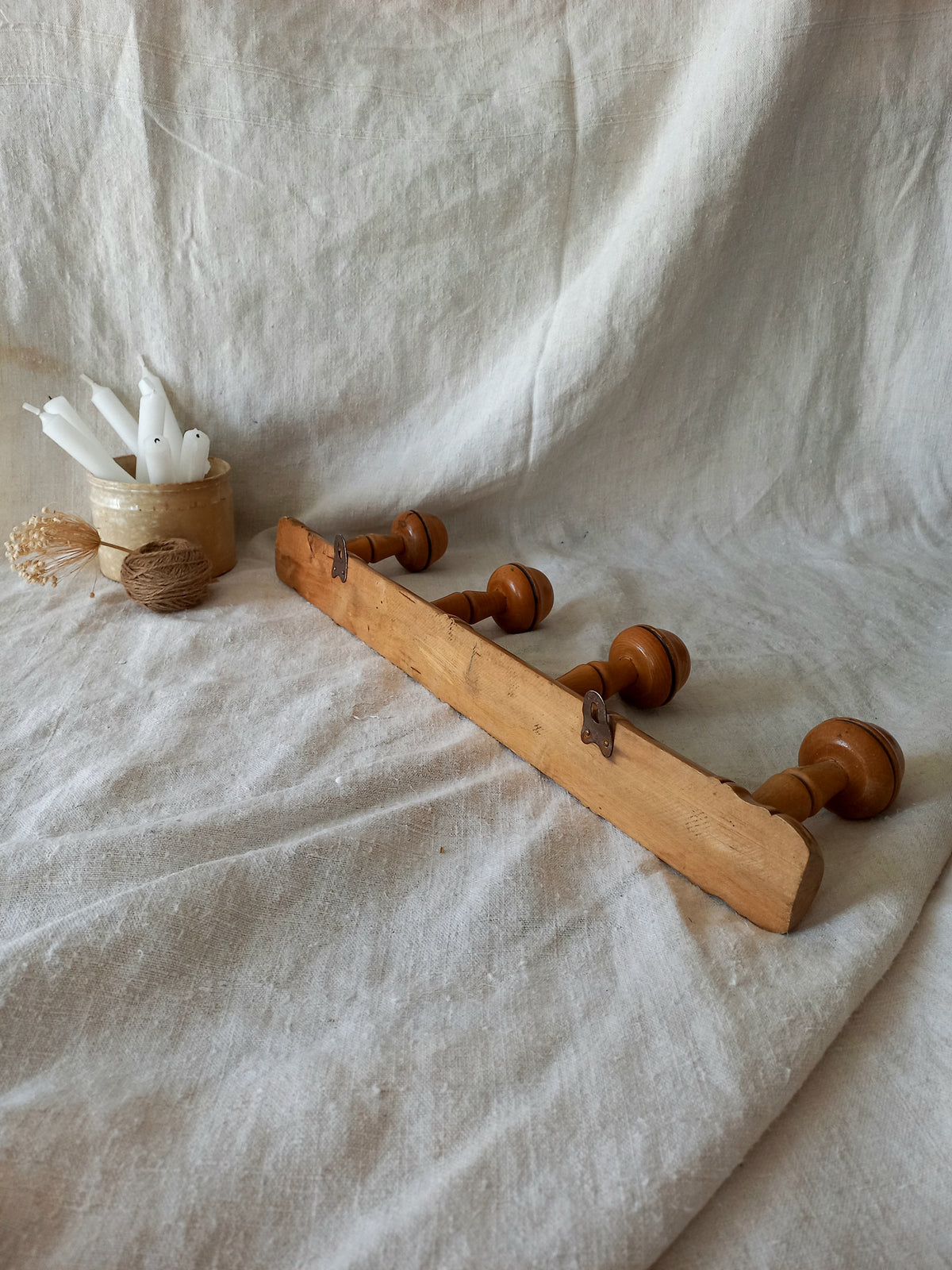 Rear of 4 peg faux bamboo wooden coat rack on a textured white fabric background