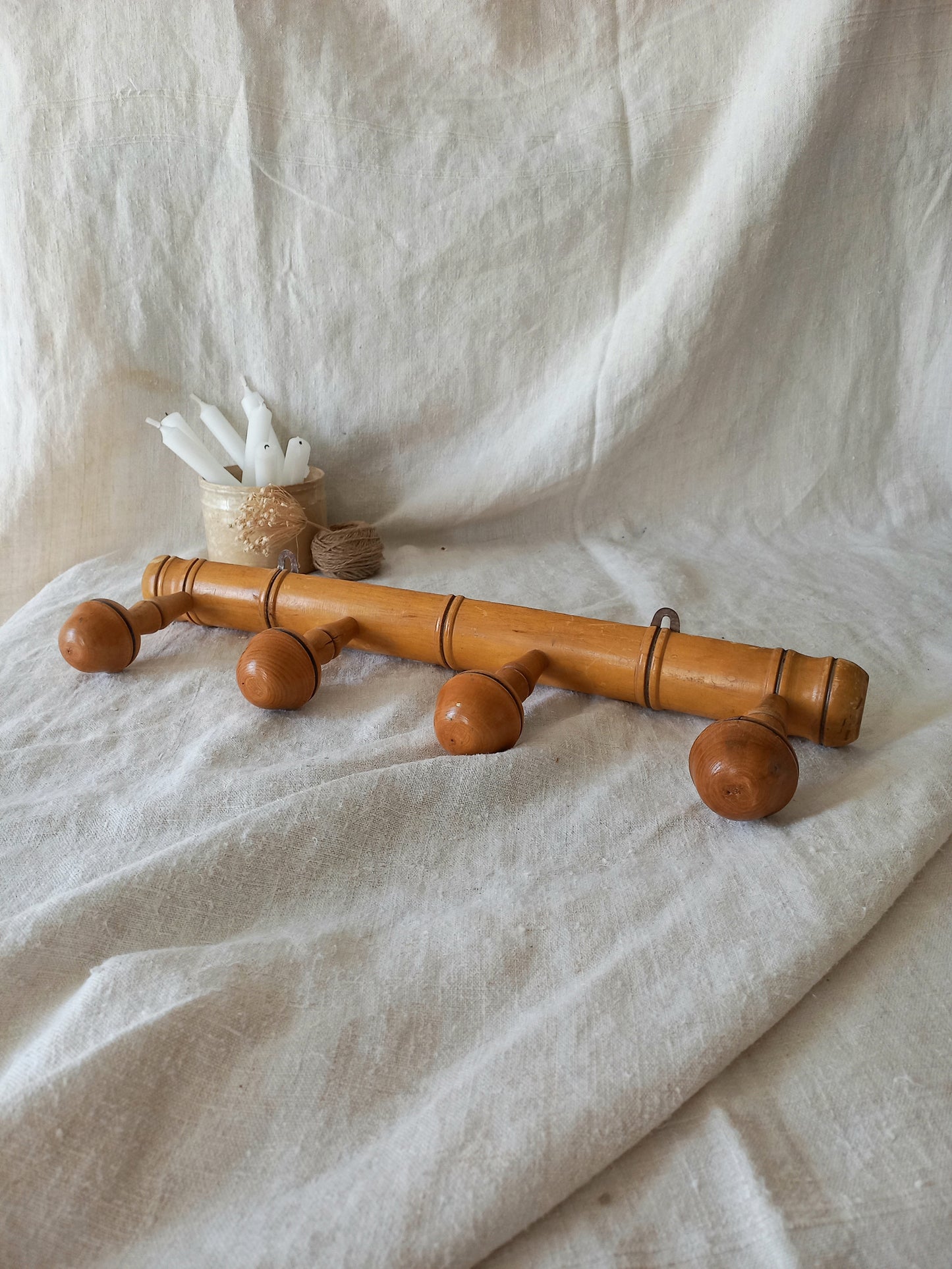 4 peg faux bamboo wooden coat rack on a textured white fabric background
