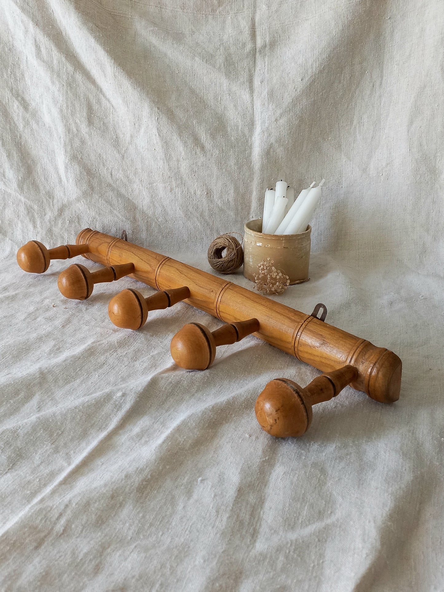 Wooden coat rack with decorative items on a textured fabric background