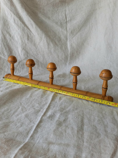 Wooden garment rack with five knobs on a textured fabric background
