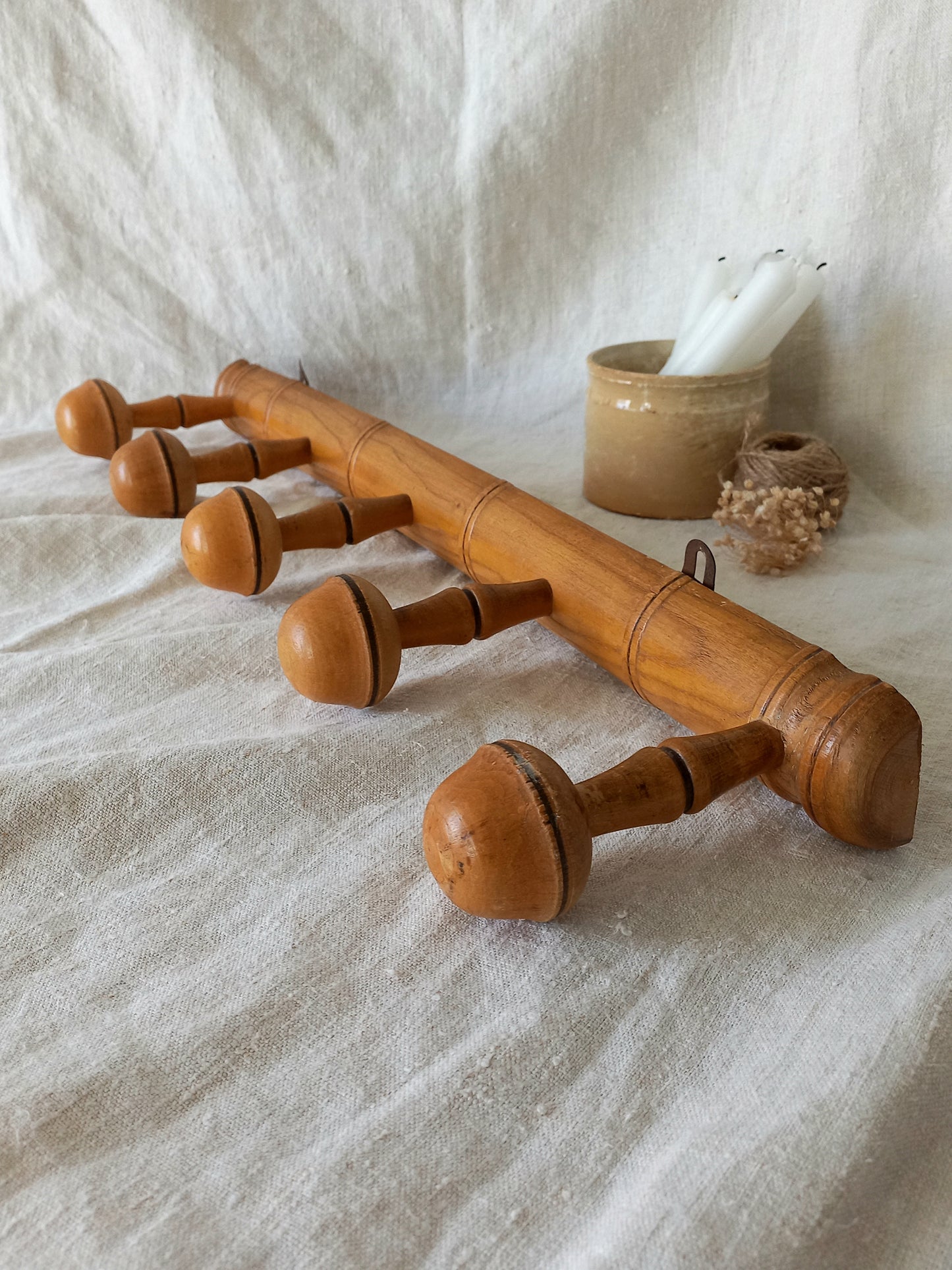 Wooden coat rack with acorn-like pegs on a textured fabric background
