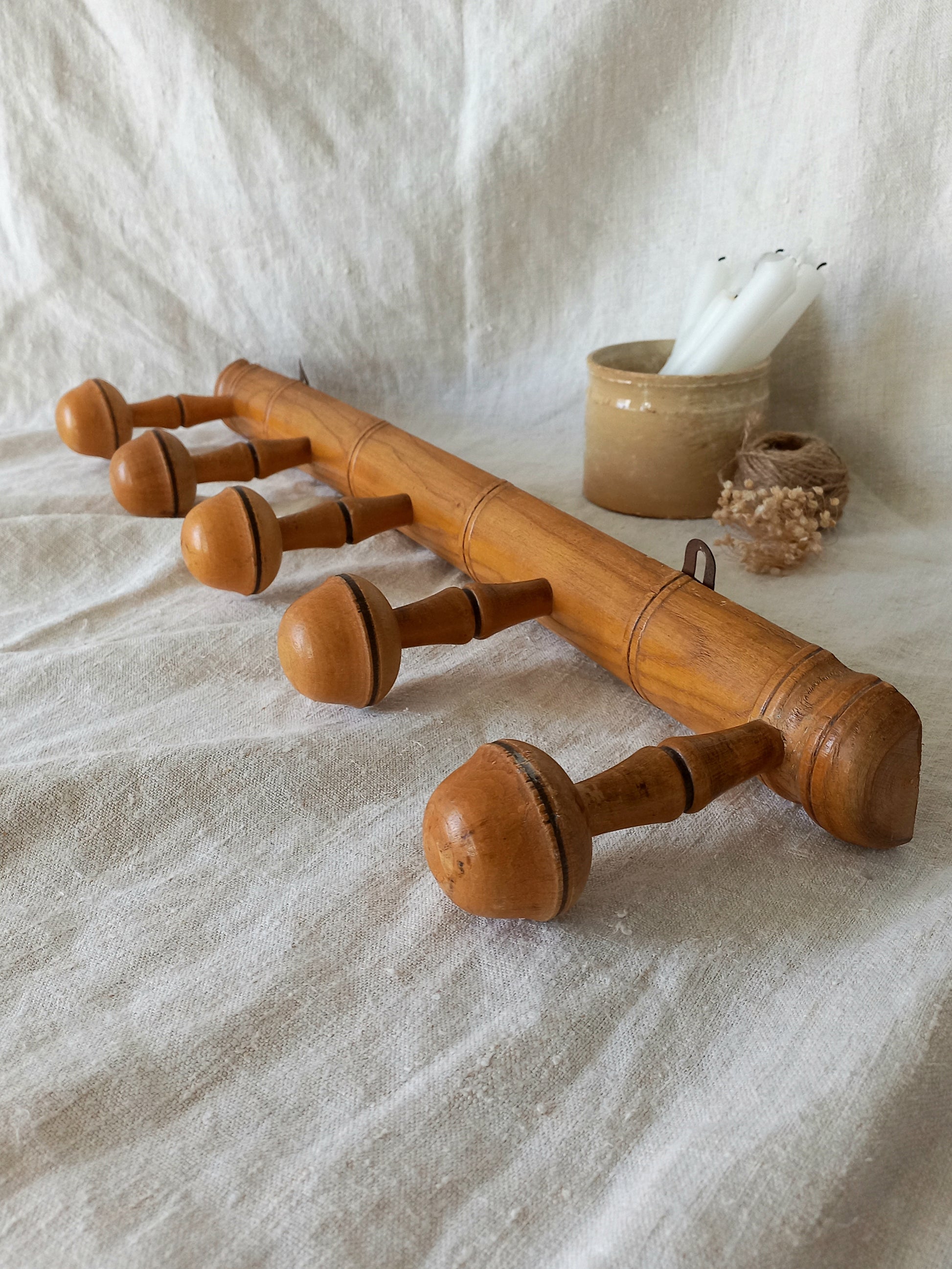 Wooden coat rack with acorn-like pegs on a textured fabric background