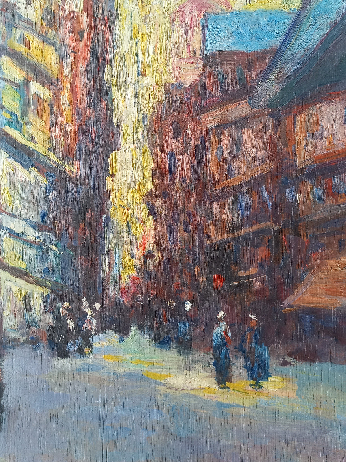 Impressionist-style painting of a narrow city street with tall buildings in warm brown, red, yellow, and blue tones, and small figures walking along the road.