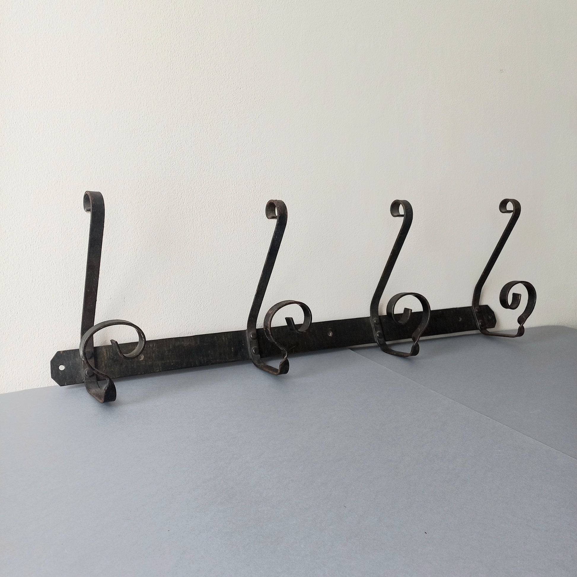 A large French vintage metal coat and hat rack for 4 coats and hats, a hand-made piece that is sturdy and can be screwed directly to your wall using the holes already in the wall bracket. The colour of the coat rack is a pleasing worn satin black with traces of gold showing through in places which give it a nice aged appearance.