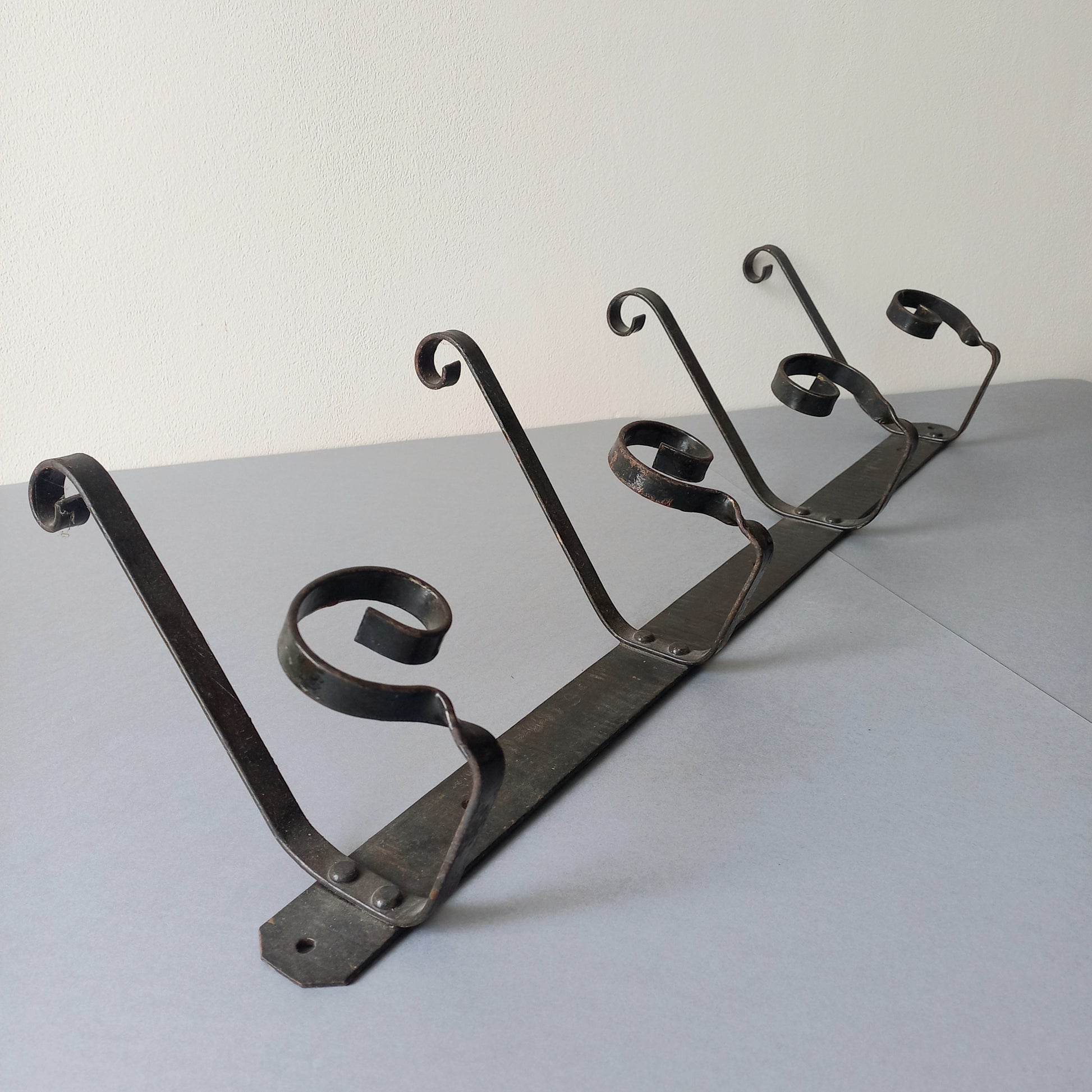 A large French vintage metal coat and hat rack for 4 coats and hats, a hand-made piece that is sturdy and can be screwed directly to your wall using the holes already in the wall bracket. The colour of the coat rack is a pleasing worn satin black with traces of gold showing through in places which give it a nice aged appearance.