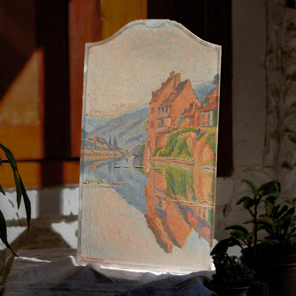 An original vintage oil painting depicting a village on the banks of a large river. It looks similar to the Rhine River Danube in Germany, and with the large hills/mountains in the background maybe the Black Forest, although it could be many places in Europe and perhaps even in France where we purchased this wonderful piece of original art on wooden board.