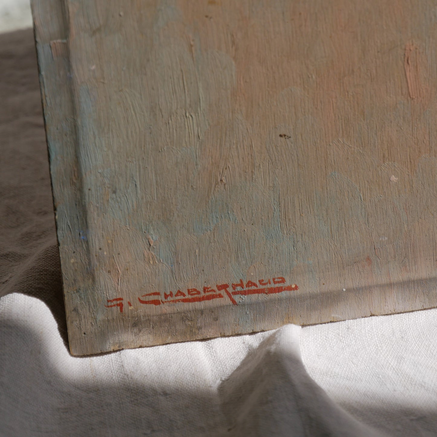 An original vintage oil painting depicting a village on the banks of a large river. It looks similar to the Rhine River Danube in Germany, and with the large hills/mountains in the background maybe the Black Forest, although it could be many places in Europe and perhaps even in France where we purchased this wonderful piece of original art on wooden board.